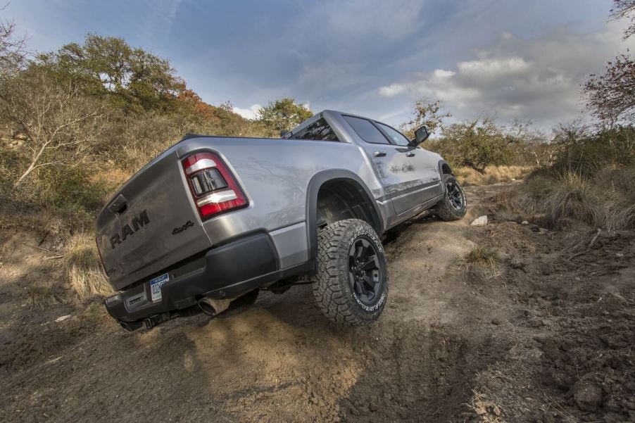 A gray Ram 1500 Rebel's suspension flexes as it navigates an off-road obstacle.