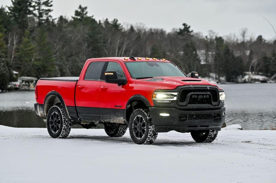 A red 2023 Ram 2500 Heavy Duty Rebel pickup truck model parked in the snow near a forest and frozen lake