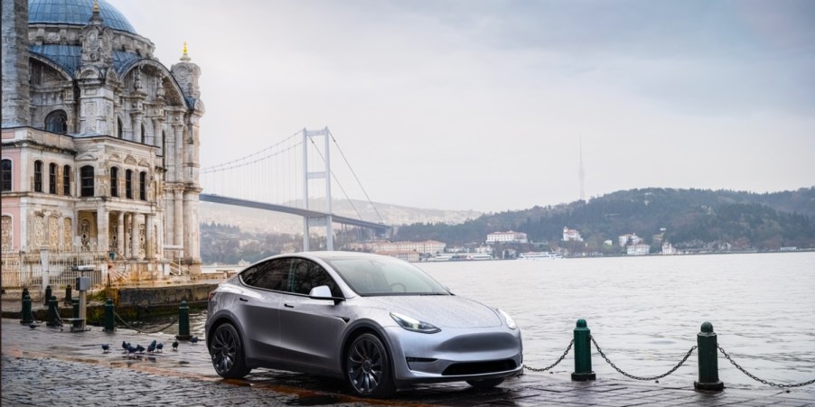 A gray 2023 Tesla Model Y is parked by the water.