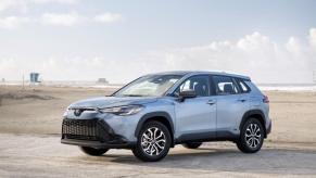 A 2023 Toyota Corolla Cross Hybrid in Celestite Gray color option parked on a sandy beach