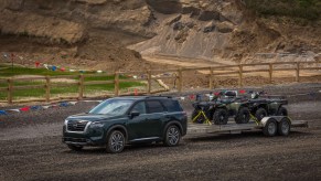 The 2023 Nissan Pathfinder in a gray-like color towing ATVs