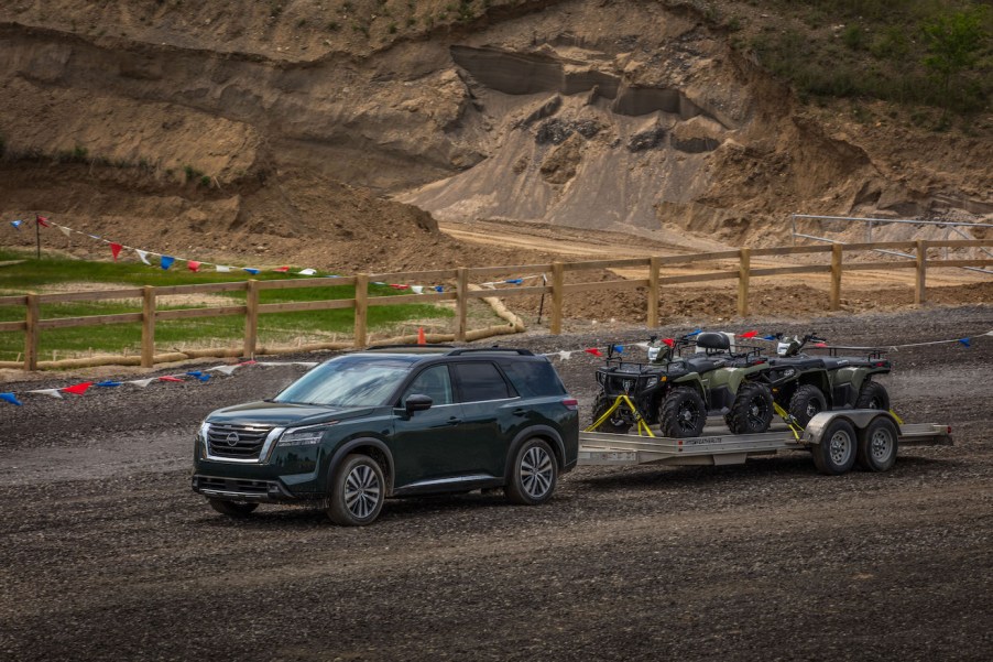 The 2023 Nissan Pathfinder in a gray-like color towing ATVs