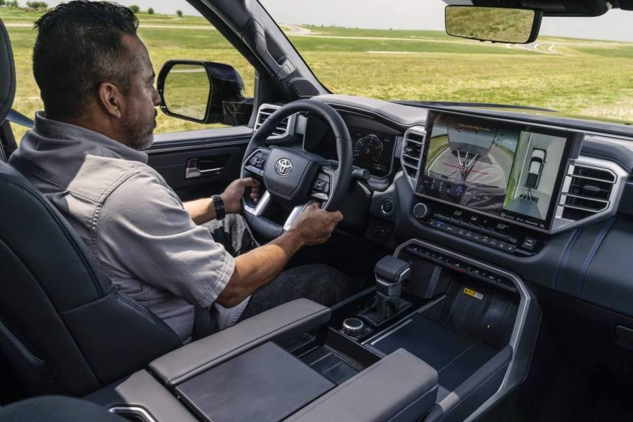 Man driving a 2023 Toyota Tundra platinum, its infotainment screen on trailering mode.