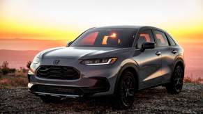 A gray 2024 Honda HR-V Sport parked on gravel before a sunset