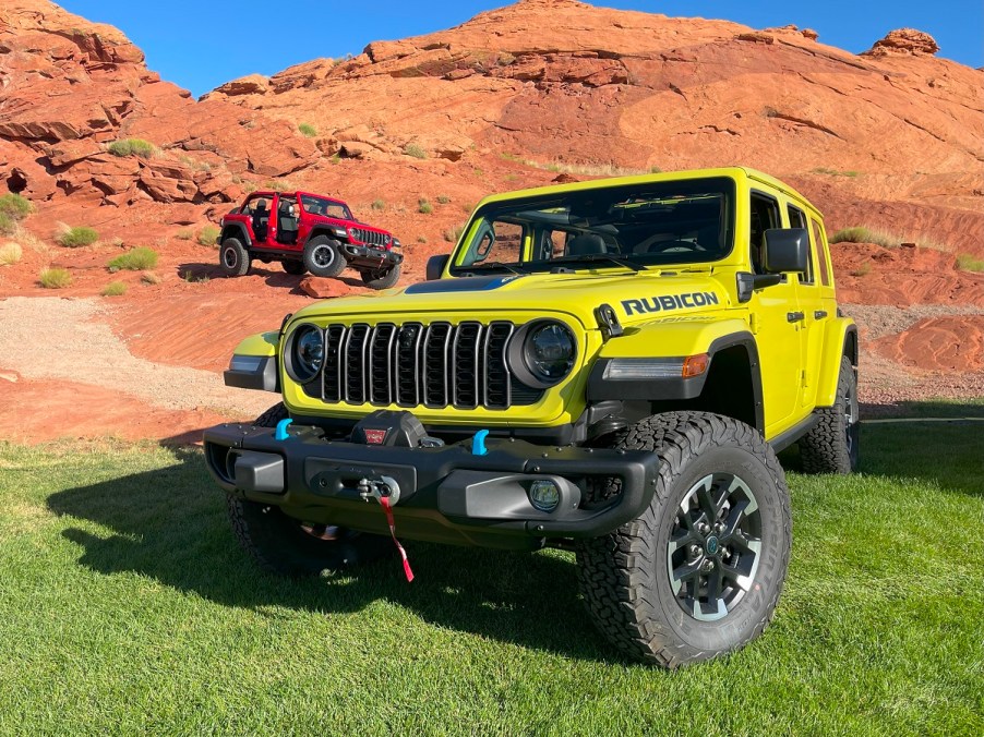 Two 2024 Jeep Wrangler models off-roading over rocks