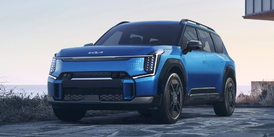 A blue 2024 Kia EV9 midsize SUV is parked. 