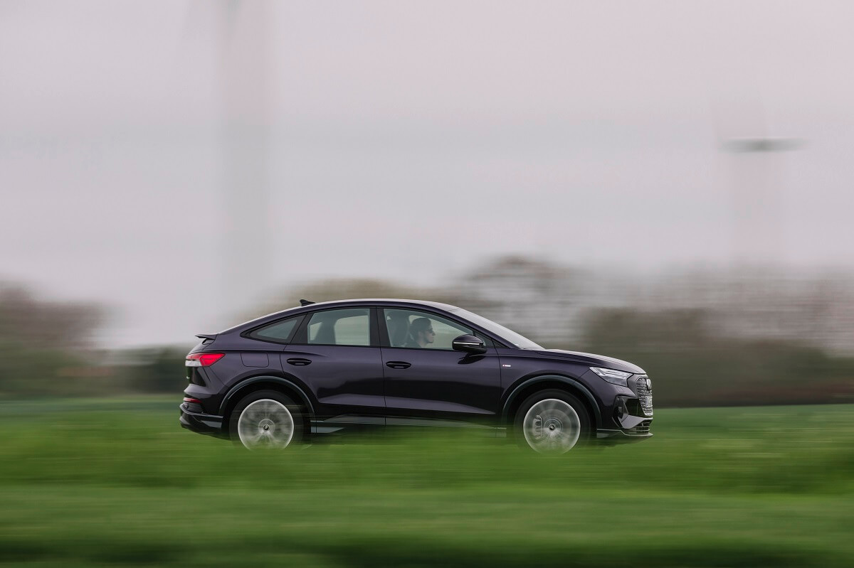 An Audi EV speeds down a German country road. 