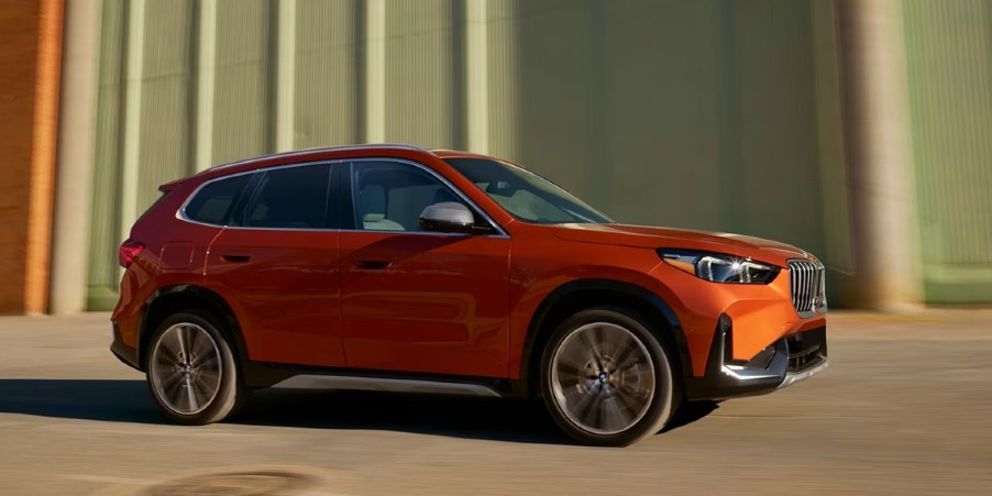 An Orange 2023 BMW X1 is driving.