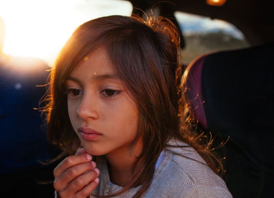 A child sits in the back of a car with an air ionizer in its HVAC filtration system which might be making them sick.