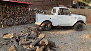 International Harvester Scout parked in front of some fire wood.