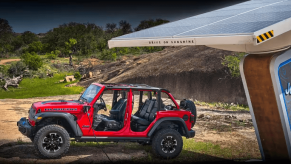 A red Jeep Wrangler Rubicon 4xe plug-in hybrid (PHEV) model near a solar-powered EV charging station