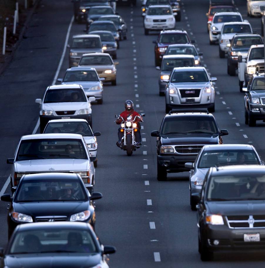 This motorcycle is lane splitting between slow-moving traffic in a state where it is legal because the local laws define and allow it.