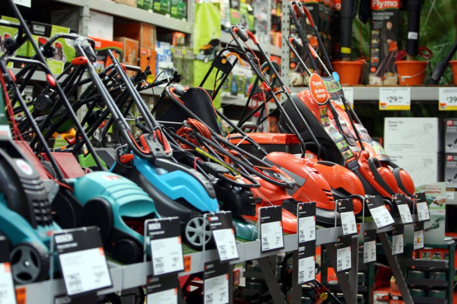 A rack displays cheap lawn mowers at a retailer. 