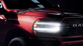 A 2023 Ram 2500 heavy-duty pickup truck model with a red paint color option and its headlights illuminated