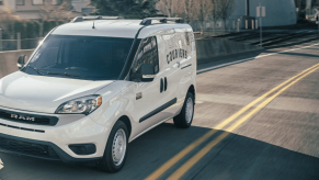 A 2022 Ram ProMaster City panel van/commercial vehicle model in white driving past concrete guard rails