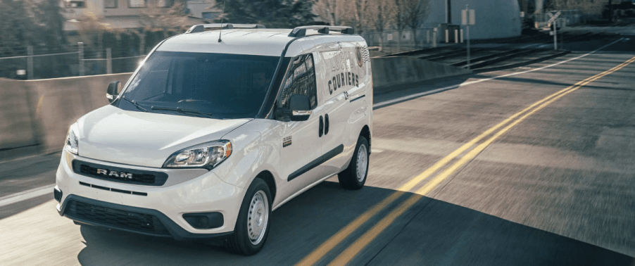 A 2022 Ram ProMaster City panel van/commercial vehicle model in white driving past concrete guard rails