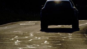 Road and tar snakes shine on a hot asphalt surface.