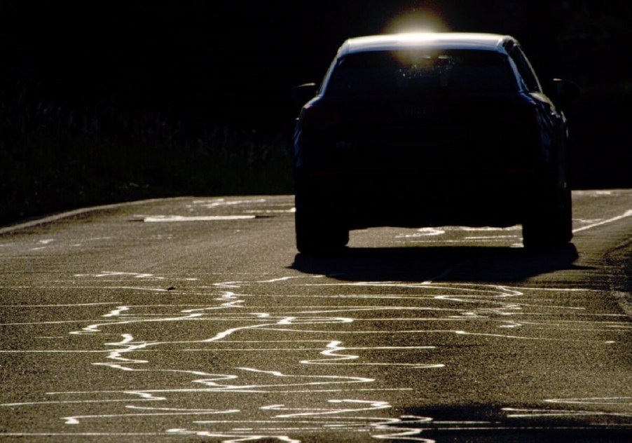 Road and tar snakes shine on a hot asphalt surface.