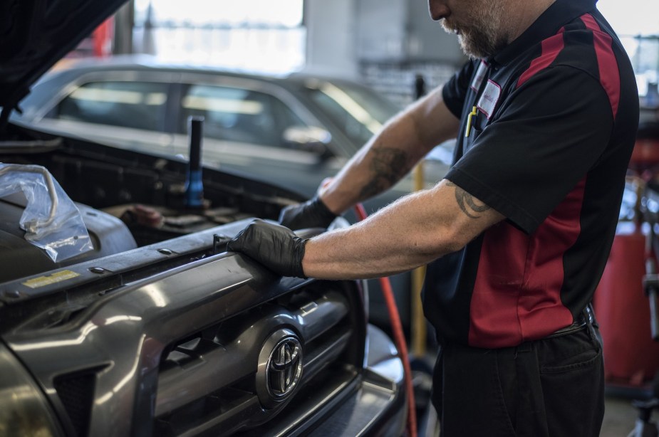 Mechanic working on the grille of a 2023 Toyota half-ton pickup truck.