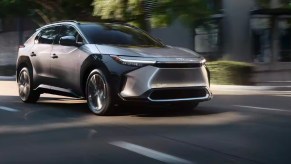 A gray 2023 Toyota bZ4X small electric SUV is driving on the road.