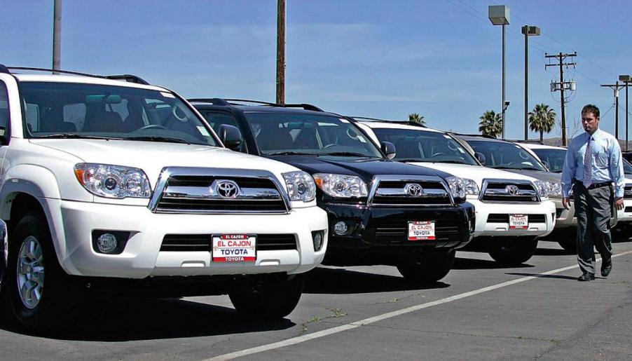 A salesmen walks by a row of used Toyota 4Runner SUVs.