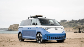 VW ID Buzz parked on the beach with a surfboard on the roof