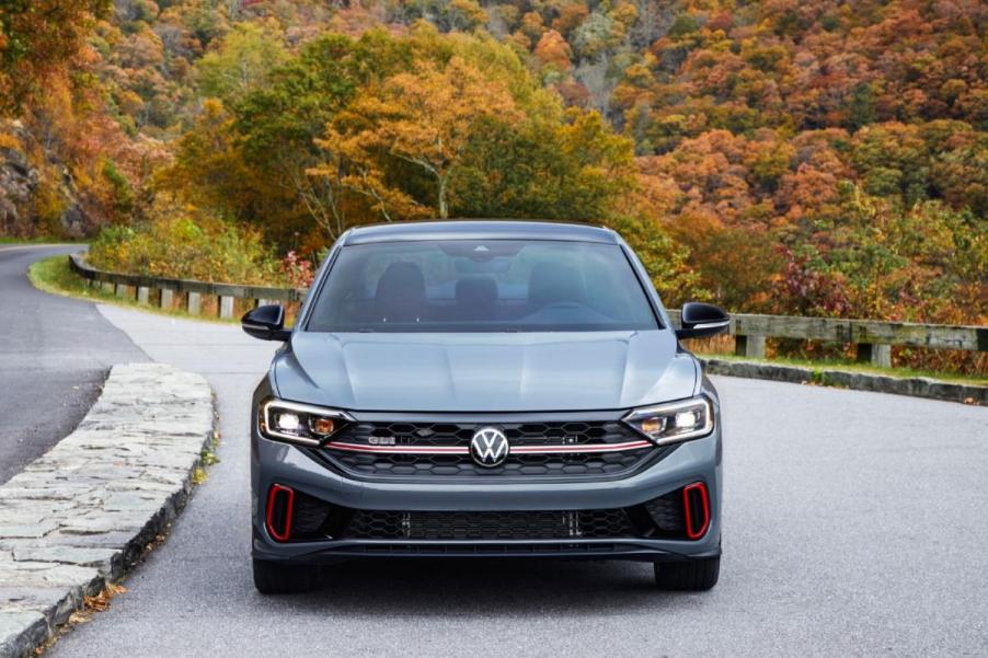 A gray Volkswagen Jetta driving down an open road.