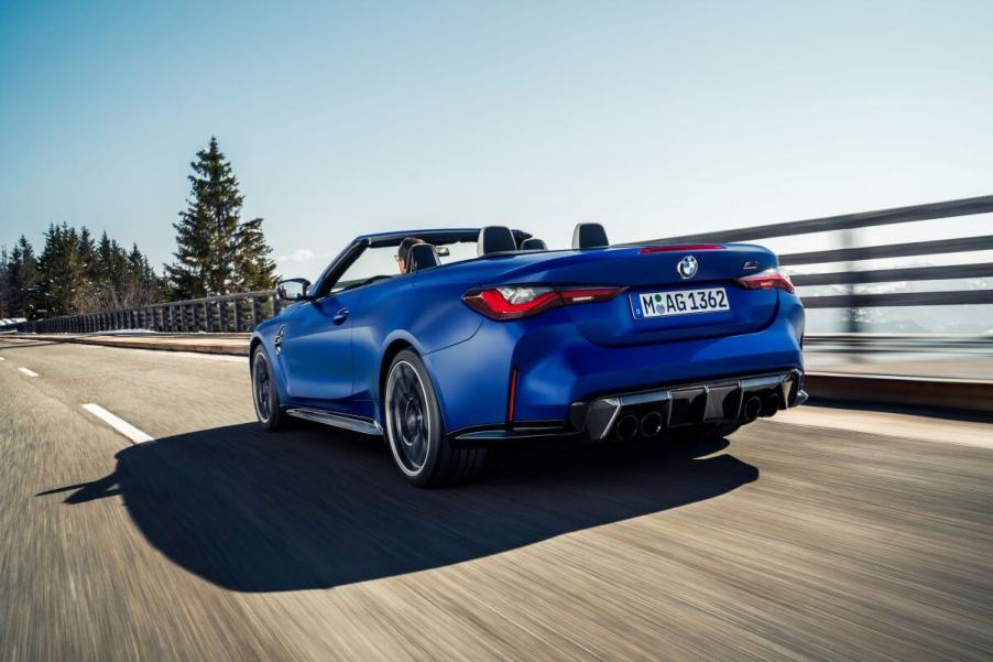 A BMW M4 Competition Convertible model driving on a highway past forest trees with xDrive