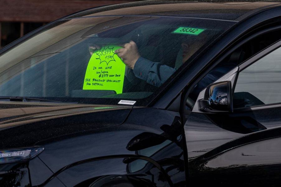 A 'For Lease' sign being added to a used car on a vehicle dealership in Richmond, California