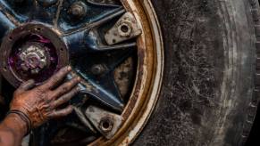 A Colombian car mechanic performing maintenance on a truck axle cap comprised of bolts and pins