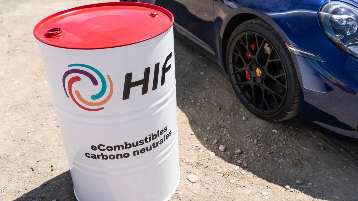 A barrel of Porsche efuel sitting next to a Porsche vehicle