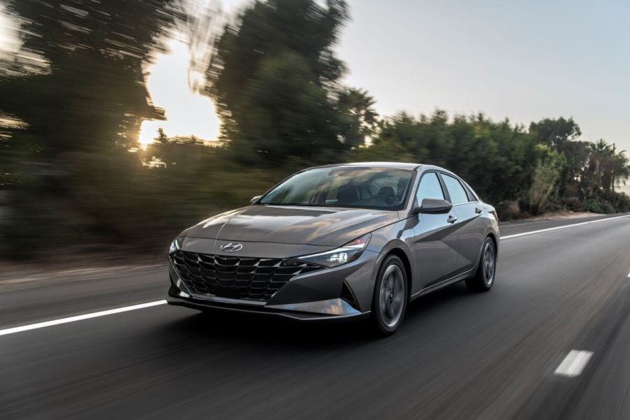 A 2023 Hyundai Elantra Hybrid compact sedan model driving down a rural highway