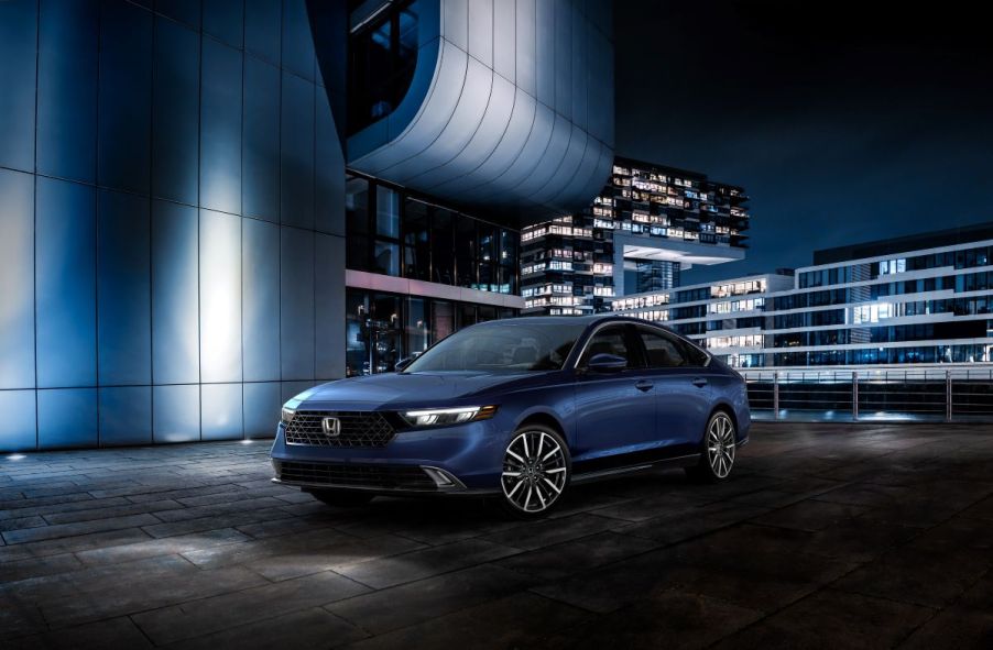 A 2023 Honda Accord Touring midsize sedan parked on a brick overlook at night framed by patio lights