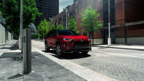 A 2023 Toyota RAV4 Prime XSE plug-in hybrid compact SUV model parked on a cobblestone road under streetlights