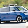 blue id.Buzz U.S. spec EV driving at speed with a surf board up top.