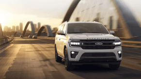 A 2024 Ford Expedition full-size SUV model driving over a bridge as the sun sets