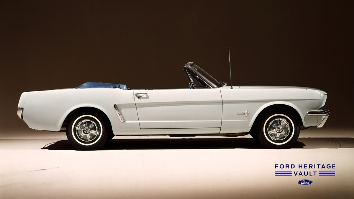 A white 1965 Ford Mustang Convertible on a stage. 