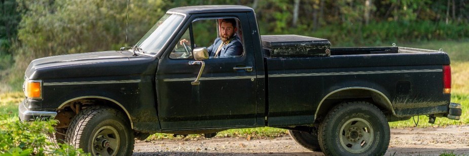 Henry Cesari driving his 1988 Ford F-150 with a regular cab and short bed, trees and fields visible in the background.