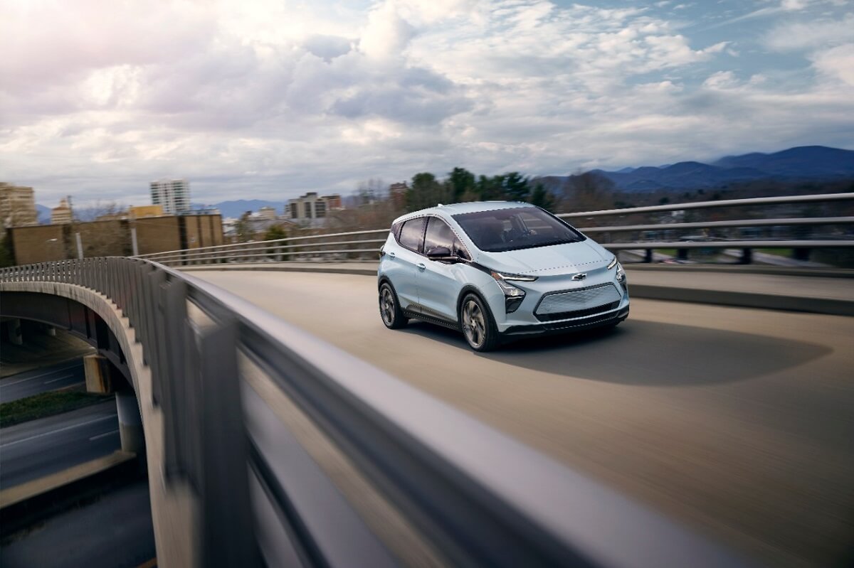 A 2023 Chevy Bolt EV drives on a city highway.