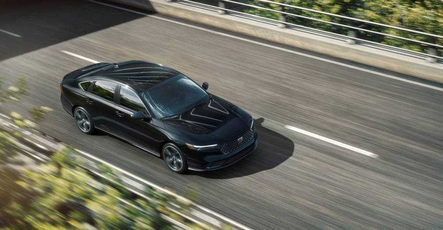 A black 2023 Honda Accord Sport driving on a city street.