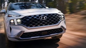 A white 2023 Hyundai Santa Fe midsize SUV is driving off-road.