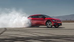 A bright red 2023 Kia EV6 GT does a burnout on a skidpad.