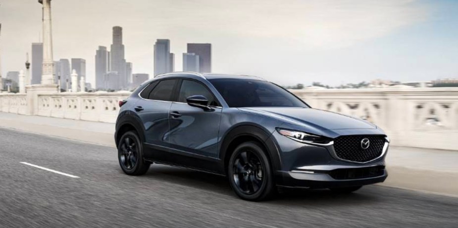 A blue 2023 Mazda CX-30 subcompact SUV is driving on the road. 