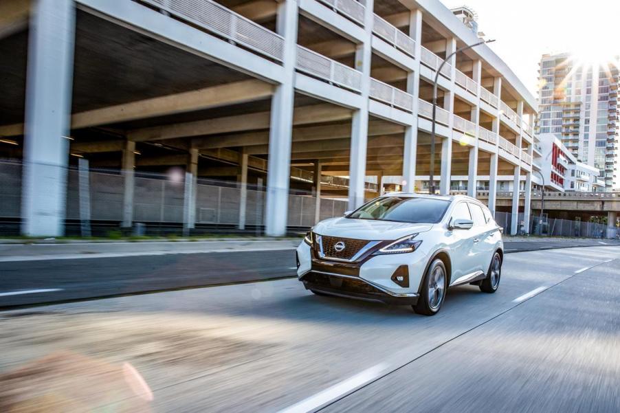 A white 2023 Nissan Murano driving down a city street.