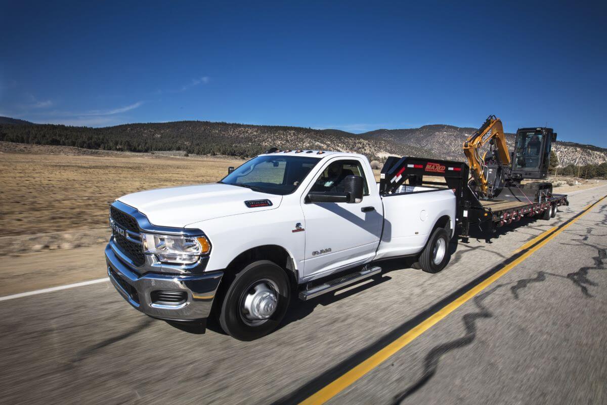 A Ram 3500 Heavy Duty Tradesman regular cab pickup truck model towing a construction crane down a highway