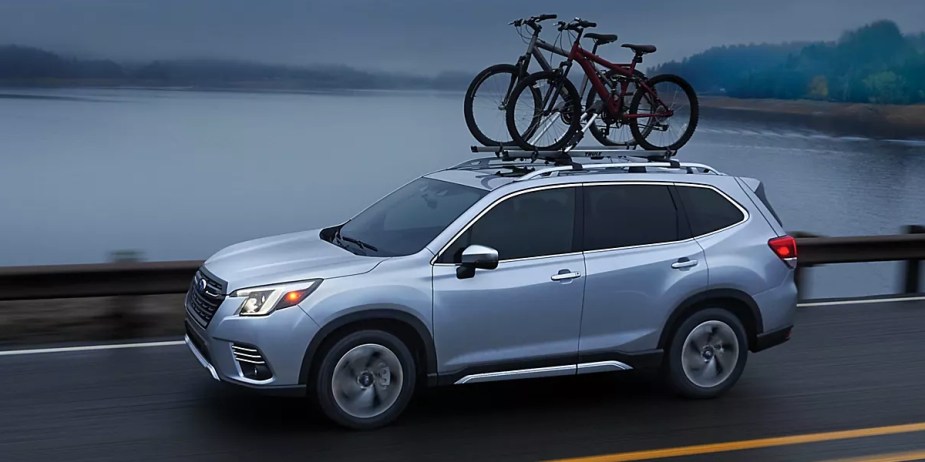 A blue 2023 Subaru Forester is driving on the road. 