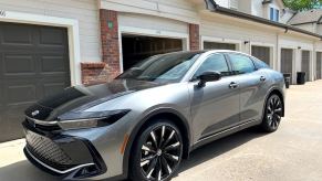 A front corner view of the 2023 Toyota Crown in front of garages.