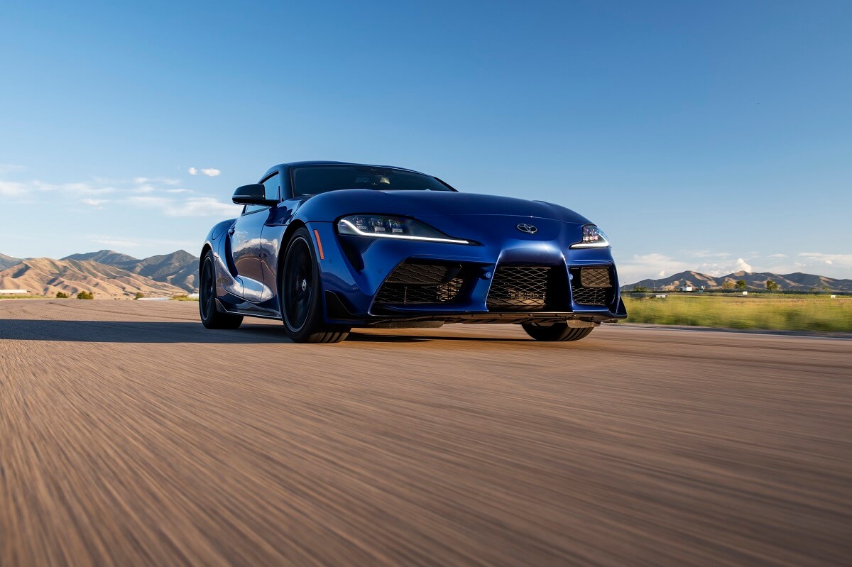 A blue 2023 Toyota GR Supra 3.0 blasts across a mountain road.