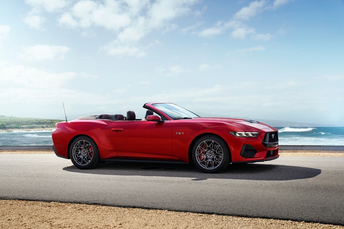 A red 2024 Ford Mustang GT Convertible parks next to the coast.