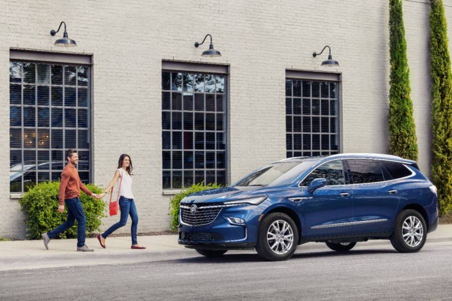 Two people walking up to a blue 2024 Buick Enclave.